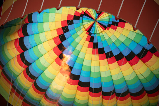 Colorful hot air balloon canopy with burner flame in flight