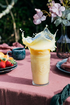 Tropical breakfast juice splash in glass on table setting