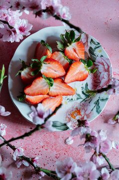 Top view of spring strawberry halves on floral plate with blossom