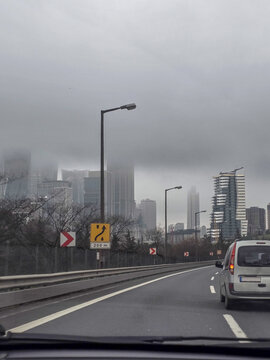 Foggy city highway drive with car and road signs ahead