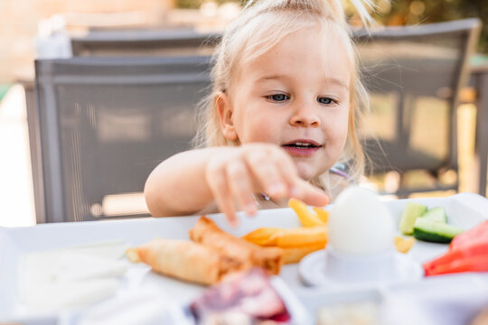 Girl enjoying breakfast on a sunny outdoor terrace table