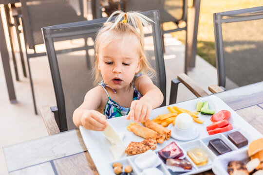 Girl enjoying breakfast on terrace table in morning light