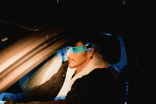Man wearing smart glasses in car at night cyber concept