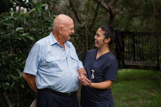 Old man having a happy conversation with a young lady in navy scrubs