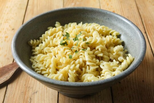 a bowl of fusilli pasta on a wooden table