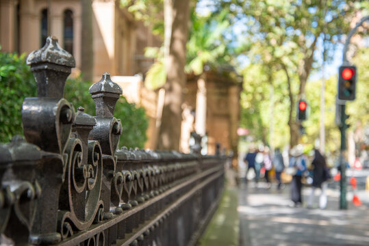 Old cast iron fence with pedestrians and traffic lights out of focus in the background