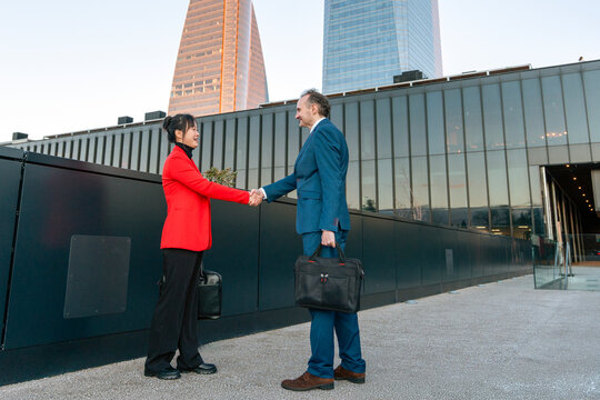 Business professionals handshake outside modern office