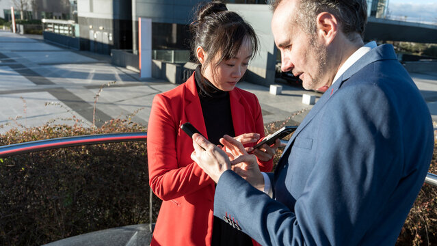 Business professionals using smartphones outdoors