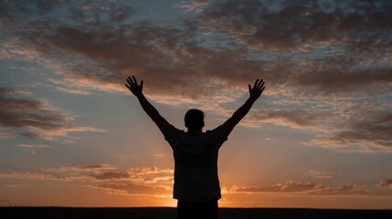Fototapeta premium Silhouette of a person with raised hands against a vibrant sunrise sky, symbolizing worship, faith, and spiritual connection.