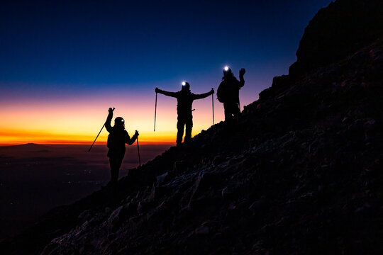 Hikers ascending mountain ridge at sunrise on a trek