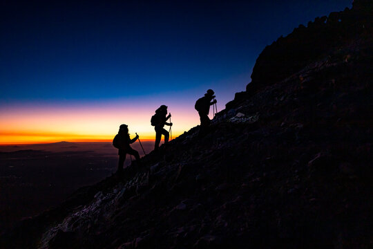 Hikers ascending mountain ridge at sunrise on rugged trek