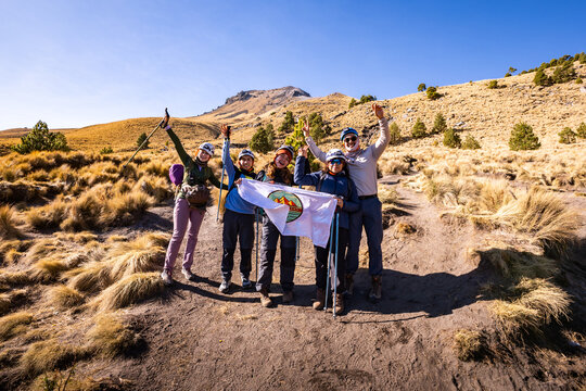 Hikers celebrating mountain summit at sunrise on trekking trail