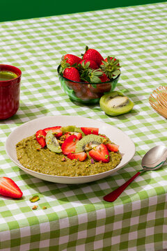 Matcha porridge with strawberry and kiwi on vichy tablecloth