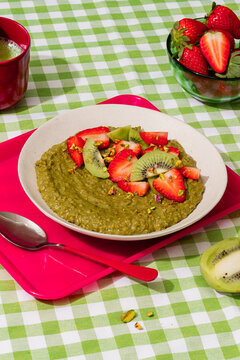 Matcha porridge with strawberry and kiwi on vichy table