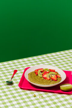 Matcha porridge with strawberry and kiwi on vichy cloth