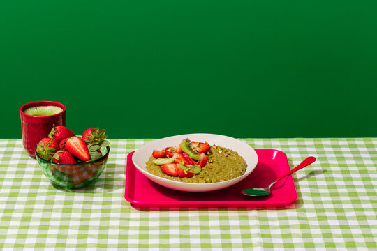 Matcha porridge with strawberry and kiwi on vichy table