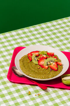 Matcha porridge topped with strawberry and kiwi on vichy