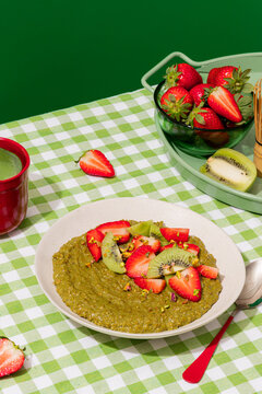 Matcha porridge topped with strawberry and kiwi on vichy