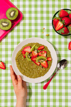 Matcha porridge with strawberry and kiwi on vichy table