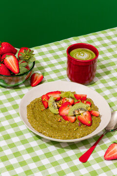 Matcha porridge with strawberry and kiwi on vichy tablecloth