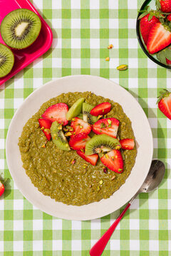 Matcha porridge with strawberry and kiwi on vichy tablecloth