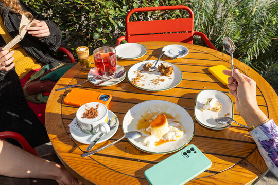 Friends sharing dessert and drinks on a sunny terrace table