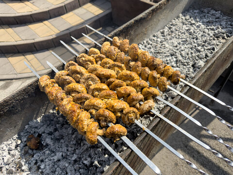 Close-up of portobello mushroom skewers grilling on charcoal