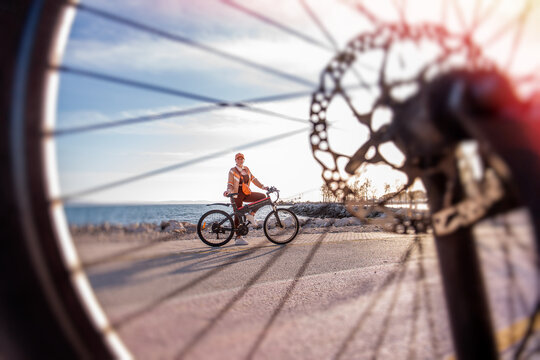 Woman with electric bicycle on coastal road at sunset