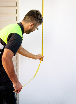 Technician measuring wall for maintenance and safety check