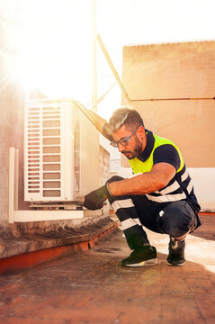 Technician performing outdoor air conditioner maintenance safely