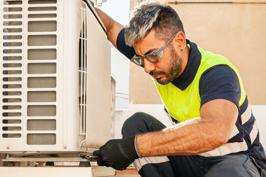 Technician performing safe air conditioner maintenance on site