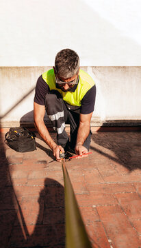 Technician measuring rooftop surface with measuring tape