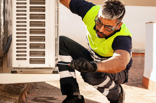 Maintenance technician servicing outdoor air conditioner unit