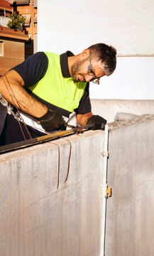 Technician with safety gear grinding metal on rooftop