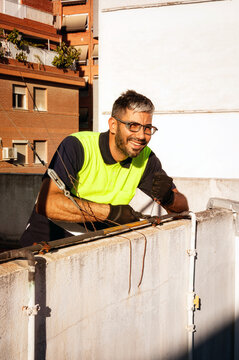Cheerful technician performing rooftop maintenance with safety gear