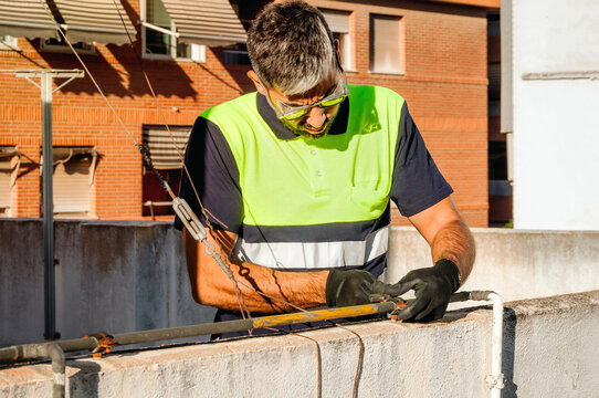Technician in safety gear doing rooftop cable maintenance