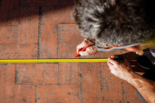 Top view of technician measuring tile floor for maintenance and safety