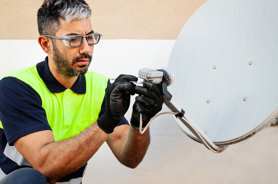 Technician performing maintenance on satellite dish