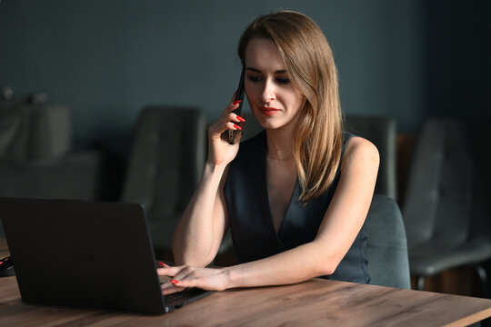 Businesswoman working on laptop while talking on phone