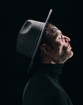 Dramatic side profile portrait of tattooed man in hat