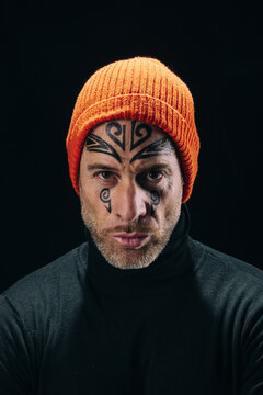 Portrait of tattooed man in orange beanie on black