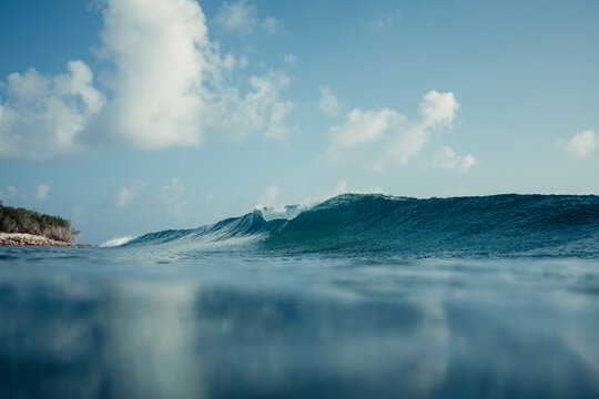 Ocean wave rolling past tropical island in Maldives sky