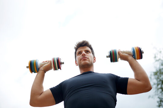 Man lifting dumbbell outdoors during strength workout