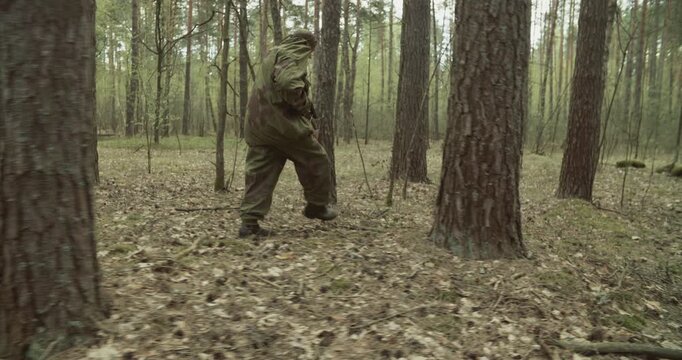 Reenactor Dressed As Russian Soviet Sniper In Camouflage Suit Sneak Carefully Through Forest. Danger Of Sudden Attack. Sniper Rifle Mosin Nagant. War Combat In Forest. Red Soviet Army Military Uniform