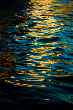 Golden light reflection rippling across deep blue water