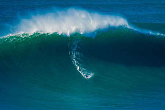 Surfer riding giant Atlantic wave off Portugal coast