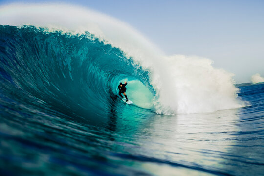 Surfer riding inside a powerful ocean barrel wave at sea