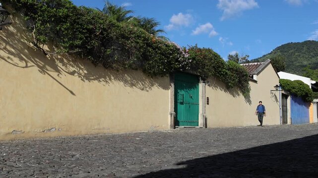 backpacker walking down scenic colonial street in antigua guatemala (backpacking latin america with large backpack) book bag back pack spanich architecture scenic tropical city