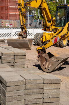 Mini excavator on a construction site renewing a sidewalk with paving stones in the old town vertical