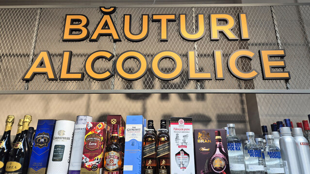 Alcoholic beverage shelf in a store with a large Romanian sign, "BĂUTURI ALCOOLICE," featuring various whiskey and vodka bottles. Picture taken on April 28, 2026 in Bucharest, Romania.